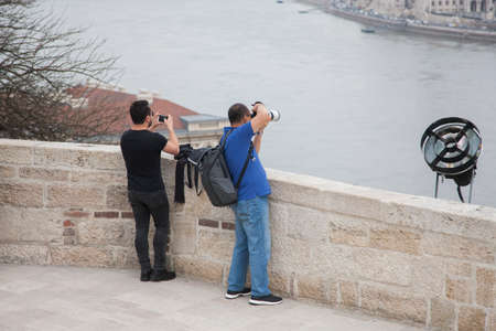 Budapest, Hungary - April 10, 2018: Male tourist with a digital camera is standing on the square and...