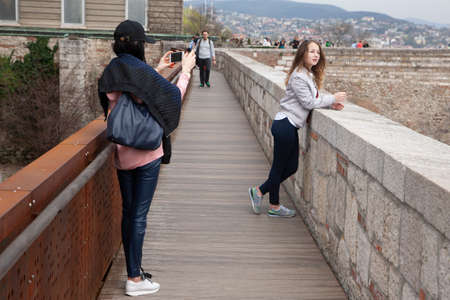 Budapest, Hungary - April 10, 2018: Woman tourist taking picture of her friend Genreのeditorial素材