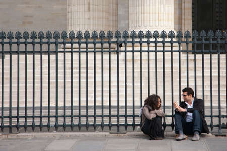 Paris, France - April 12, 2011: young woman and man sitting together near fenceGenreのeditorial素材
