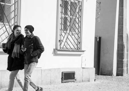 Prague, Czech Republic - March 14, 2017: Young couple drinking coffee while walking down the street. Genre Black and white imageのeditorial素材