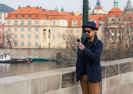 Prague, Czech Republic - March 14, 2017: Handsome hipster male with beard in sunglasses texting messages Genreのeditorial素材