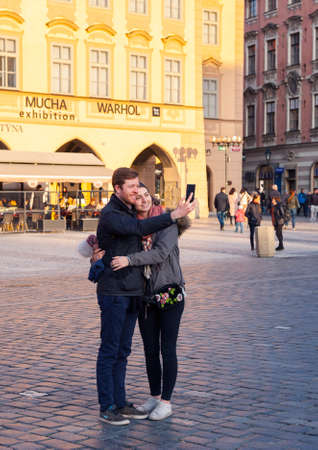 Prague, Czech Republic - March 15, 2017: Happy young couple in love takes selfie portrait on the street Pretty tourists make funny photos for travel blog in Europe. Genreのeditorial素材