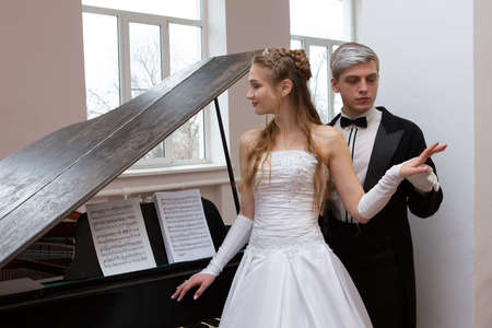 Young good looking couple in evening dress and dress coat posing in elegant way in a classical style Portraitの写真素材