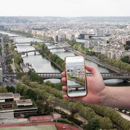 Scenic view of historical center Paris bridge and buildings of old town Hand with a smartphone, on the screen of which the urban landscape Landscapeの写真素材