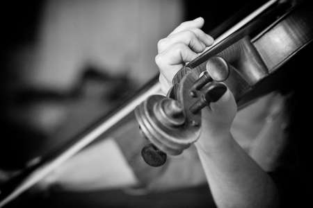 Young beautiful woman violin player looking at camera over instrument on her shoulder holding bow. Black and white image Close-upの写真素材