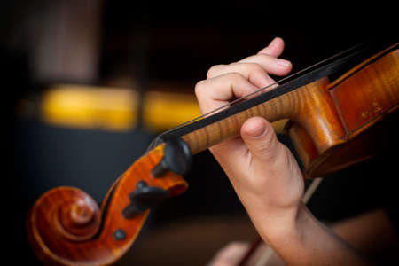 Girl playing the violin. Hand of a girl and a fiddle. Close-up portraitの写真素材