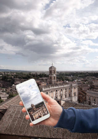 Scenic view of historical center Rome Hand with a smartphone, on the screen of which the urban...