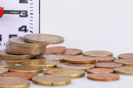 Pile of Euro coins isolated on white background. Global, Time and Business concept. Vintage round clock on stack of coins Limited depth of field Close-upの写真素材