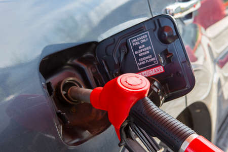 Fill the car with fuel. The car is filled with gasoline at a gas station. Gas station pump. Man refueling gasoline with fuel in a car, holding a nozzle. Limited depth of field. Blurred image Close-up.の写真素材