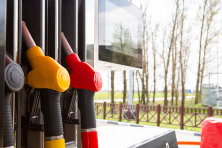 Close-up fuel nozzles on petrol and diesel fuel. Gas station pump. Man refueling gasoline with fuel in a car, holding a nozzle. Limited depth of field. Blurred imageの写真素材