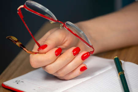 Luxury short manicure Red nails design. female hand holding glasses Limited depth of field Close-upの写真素材