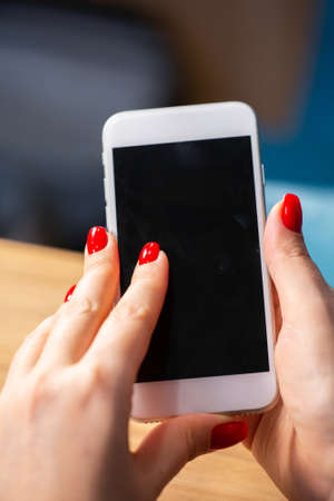 close-up, female hands with red manicure use a smartphone on a white background. Limited depth of field Close-upの写真素材