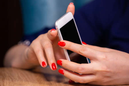 close-up, female hands with red manicure use a smartphone on a white background. Limited depth of field Close-upの写真素材