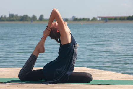 Beautiful woman practicing Yoga by the lake Portrait