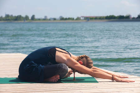 Beautiful woman practicing Yoga by the lake Portrait