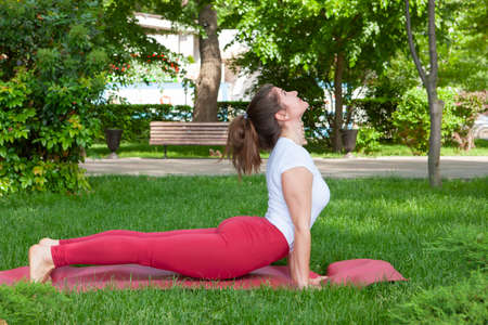 Smiling girl in the park exercise on the yoga mat, high lunge Portrait