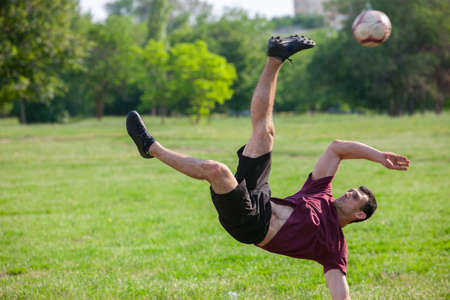 Young man playing football in park keeping ball in the air Soccerの写真素材