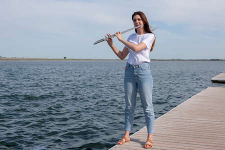Beautiful woman playing flute in Waterfront Smiling woman. Portraitの写真素材