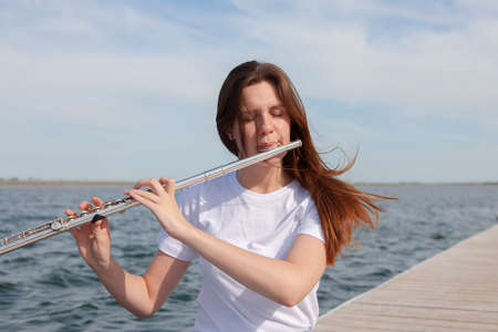 A beautiful woman posing in beach while playing on a flute. Portraitの写真素材