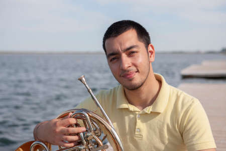 Portrait of teen musician playing instrument classic french horn. Close-up