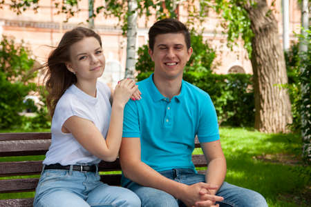 beautiful young couple sitting on a bench in the park. Portraitの写真素材