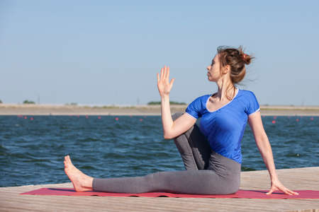 Woman making yoga exercise at a lake. Portrait