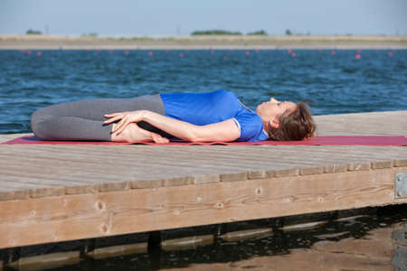beautiful caucasian woman exercising yoga in nature next to a lake. Portrait