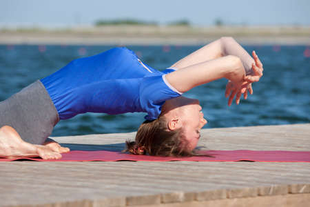 beautiful caucasian woman exercising yoga in nature next to a lake. Portrait