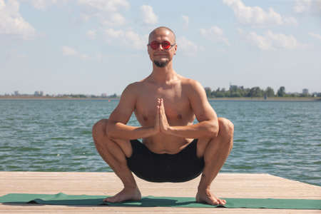 Profile shot of mature man meditating in lotus position on pier against lake Portrait