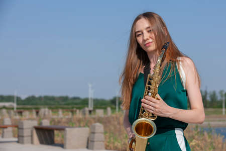 Young woman with saxophone with nature background. Portraitの写真素材