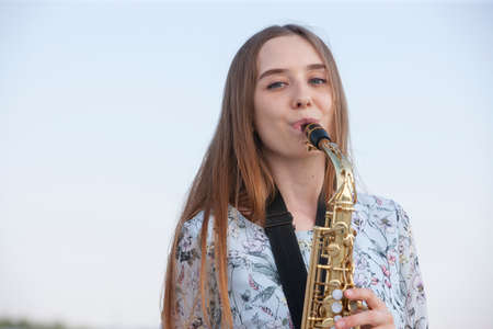 Young woman with saxophone with nature background. Portraitの写真素材