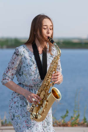 Young woman with saxophone in the park. Portraitの写真素材