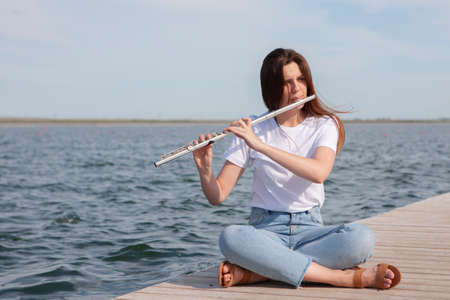 A beautiful woman posing in beach while playing on a flute. Portraitの写真素材
