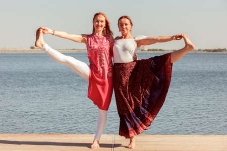 Two mature women keeping fit by doing yoga in the summer. Portraitの写真素材