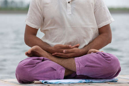Young man doing yoga and meditating in warrior pose on beach Portrait
