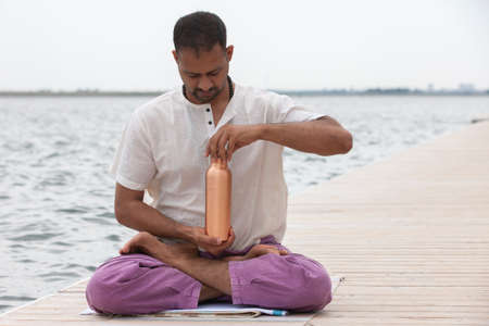 Man doing yoga on a wooden floor in the nature. Fresh water conservation concept. Portraitの写真素材
