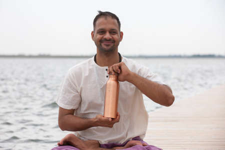Man doing yoga on a wooden floor in the nature. Fresh water conservation concept. Portrait