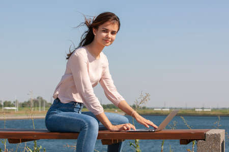 Young woman with a laptop on a park bench. Portrait.