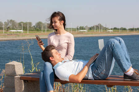 happy young couple using laptop while sitting together in park. Portrait.の写真素材