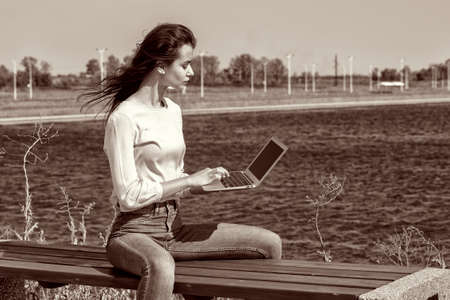Young woman with a laptop on a park bench. Portrait.