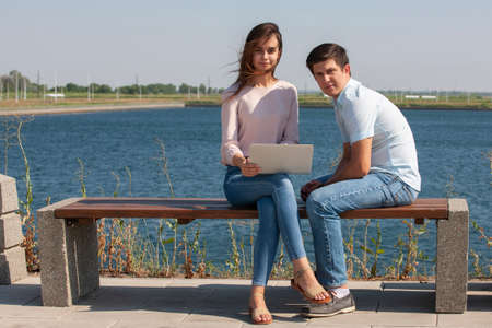 Man and woman using laptop outdoors. Image of young couple man and woman in casual clothes. Portrait.の写真素材