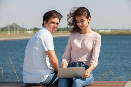 Man and woman using laptop outdoors. Image of young couple man and woman in casual clothes. Portrait.の写真素材