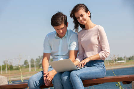 Couple using a laptop outdoors and looking happy. Portrait.の写真素材