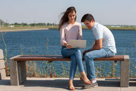 Man and woman using laptop outdoors. Image of young couple man and woman in casual clothes. Portrait.の写真素材