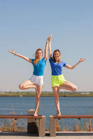 Two young women doing yoga at nature. Fitness, sport, yoga and healthy lifestyle concept. Portraitの写真素材