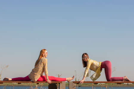 Yoga in the park - meditation and breathing exercises with an experienced trainer, Portrait of two womenの写真素材