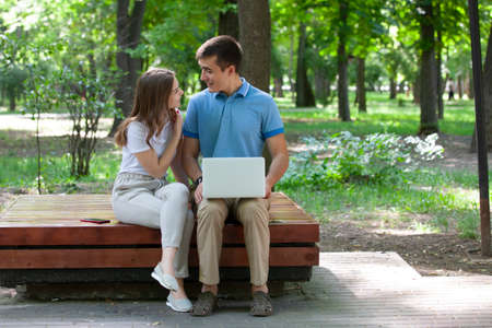 A guy and a girl are reading a book in a city park on a hot summer day. Students relax on a green lawn and read a book.の写真素材