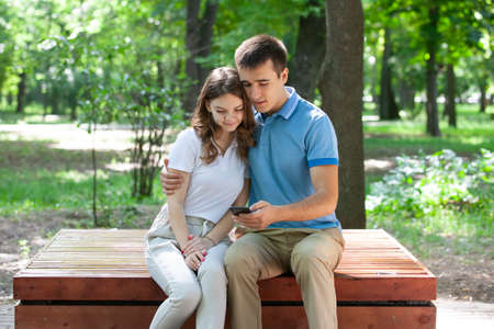 beautiful young couple sitting on a bench in the park. Portraitの写真素材