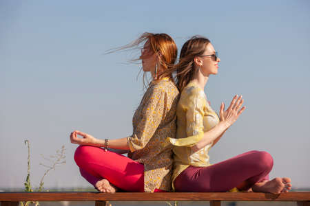 two adult women aged yoga outdoors in summer in the park. Portraitの写真素材