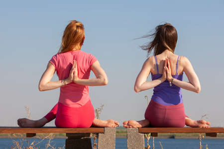 two adult women aged yoga outdoors in summer in the park. Portraitの写真素材